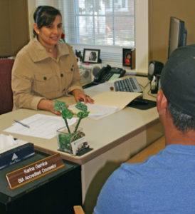 Karina Garnica helps a client in the Immigration Office of the Diocese of Davenport in this file photo.