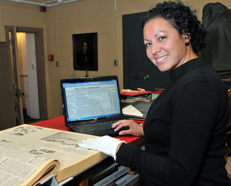 Lindsay Steele Tyla Cole, archivist for the Diocese of Davenport, looks at an archived copy of The Catholic Messenger online. A paper edition also sits on the counter. All copies of the Catholic Messenger from 1883 to 2012 are online for free.