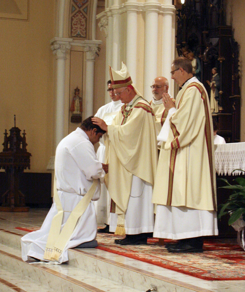 Anne Marie Amacher Bishop Martin Amos lays hands on Guillermo Trevino during the ordination ceremony June 6.