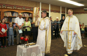 Barb Arland-Fye Deacon Sergio Ayala processes with the Book of the Gospels, followed by Father Bryan Eyman, Protopresbyter for the Midwest Region of the Byzantine Catholic Eparchy, during a Divine Liturgy Aug. 8 in the St. Vincent Center, headquarters of the Diocese of Davenport. 