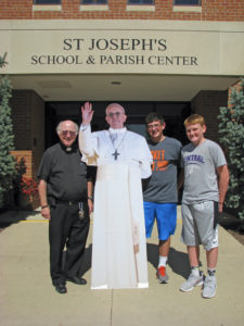Contributed Pope Francis “stopped” by St. Joseph Catholic School in DeWitt. Standing with the cardboard cutout of the pope are Father Paul Connolly and eighth graders Will Martin and Tucker Kinney.