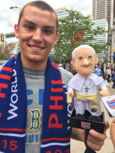 Contributed Jacob Menster, a junior at the University of Iowa, shows off a scarf and a Pope Francis doll he purchased in Philadelphia. While the students were unable to get close to the pope during the Mass Sept. 27 on Benjamin Franklin Parkway, the group had a life-changing visit anyway.