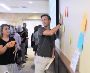 Lindsay Steele Student teacher Kristen Winter and Regina science teacher Chris Murdock post sticky notes listing the traits of spirit-filled teachers during a diocesan in-service for Regina Catholic Education Center teachers and administrators Aug. 19 at St. Patrick Parish in Iowa City.