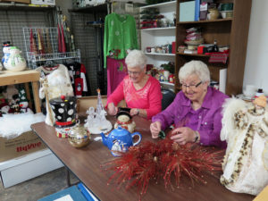 Anne Marie Amacher Pat Bushur, left, and Irene Gannon mark items for the upcoming Christmas Open House at Cinderella’s Cellar in Davenport. Proceeds from the resale shop benefit The Kahl Home. 