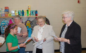 Kate Marlowe Kiely DeBo, a fifth-grade student at Prince of Peace School in Clinton, presents Sister Dorothy Mae Stolmeier, OSF, with a card she made as part of National Do Something Nice Day. Also present to receive cards from the fifth-grade class were Sister Virgina Krakow, OSF, left, and Sister Hilary Mullany, OSF.
