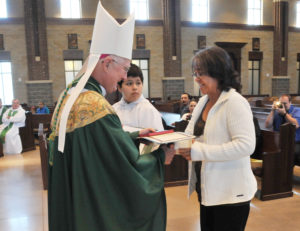 Lindsay Steele Alicia Rivas, a member of Ss. Mary & Mathias Parish in Muscatine, receives her Ministry Formation Program certificate from Bishop Martin Amos Oct. 3 at St. Patrick Catholic Church-Iowa City as altar server Aaron Loya looks on.