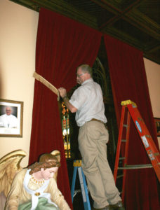 Anne Marie Amacher Steve Seifert hangs red velvet drapes that will mark the Holy Door at Sacred Heart Cathedral in Davenport. Marie Johnson of State Street Interiors and Furniture in Bettendorf worked with the worship and spirituality committee at the cathedral to come up with the design.