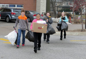 Anne Marie Amacher From left, Sean Thompson, Yuliana Marceleno, Nate Parchert and Sydney Newberry carry bags full of toilet paper to a trailer to be delivered to The Center in Davenport. All Saints Catholic School in Davenport collected toilet paper and donations on Jan. 15 to give to people in need.