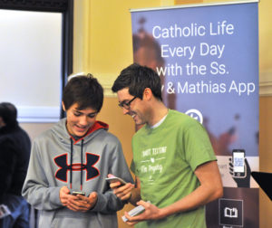 Lindsay Steele  Tommy Fallon, right, youth and young adult ministry coordinator for Ss. Mary & Mathias Parish in Muscatine, shows Mitchell Paca how to use the new parish application (app). The parish recently launched the app as a way to evangelize and transmit information through an additional medium.