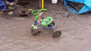 Ann Garton A child's tricycle is caked in mud at The Jungle refugee camp. Mud - a mixture of soil and human waste - is a common occurrence at the camp.