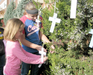 Contributed St. Joseph Catholic School-DeWitt students Kerrigan and Lily Jefford attach paper crosses in memory of a loved one to a tree outside the school. The activity is an example of how schools in the Diocese of Davenport have been incorporating the Year of Mercy into school curriculum. 