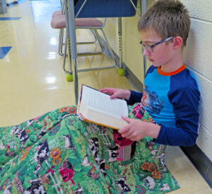 Anne Marie Amacher Third-grader Charlie Lane reads one of the Harry Potter books as part of a reading challenge reward. Students at St. Paul the Apostle Catholic School in Davenport exceeded their holiday reading challenge and got to wear pajamas to school Jan. 14, have an hour of free reading time and drink hot chocolate.