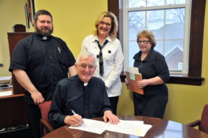 Lindsay Steele Bishop Martin Amos signs the first shorter process annulment in the Diocese of Davenport on Feb. 2. Also with bishop are Father Paul Appel, judicial vicar; Beth Blough, tribunal auditor; and Kathy Lanztky, tribunal secretary.