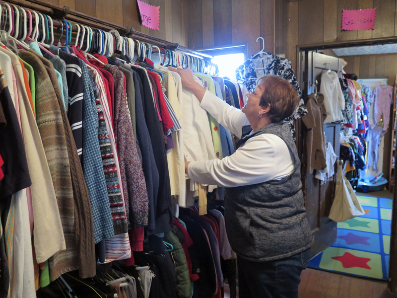 Anne Marie Amacher Chris Brown hangs up an item in the Sacred Heart Cathedral Clothing Center in Davenport. The center is staffed by volunteers. Twice a week patrons can pick up clothing for free. 