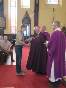 Anne Marie Amacher Nick Den Hartog of St. Mary Parish in Oskaloosa receives the “Ad Altare Dei”(to the Altar of God” religious emblem from Bishop Martin Amos. A diocesan wide scouting Mass and religious emblems ceremony was held at Sacred Heart Cathedral in Davenport Feb. 28.