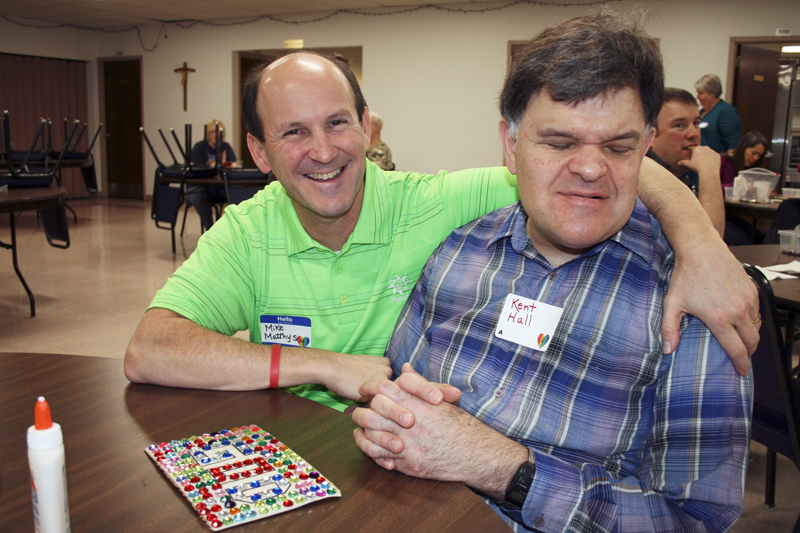 Barb Arland-Fye Mike Matthys, left, and Kent Hall show off Kent’s artwork during a renewal day for adults with disabilities, their family, friends and caregivers Feb. 27. The event was held at Our Lady of Victory Parish in Davenport.