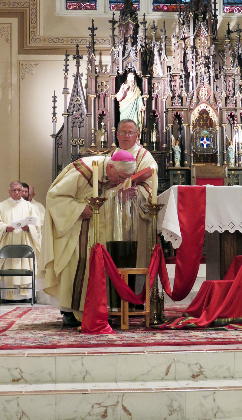 Anne Marie Amacher Bishop Martin Amos blesses the Sacred Chrism during the annual Chrism Mass March 14 at Sacred Heart Cathedral in Davenport. Also pictured is Deacon Dan Huber.