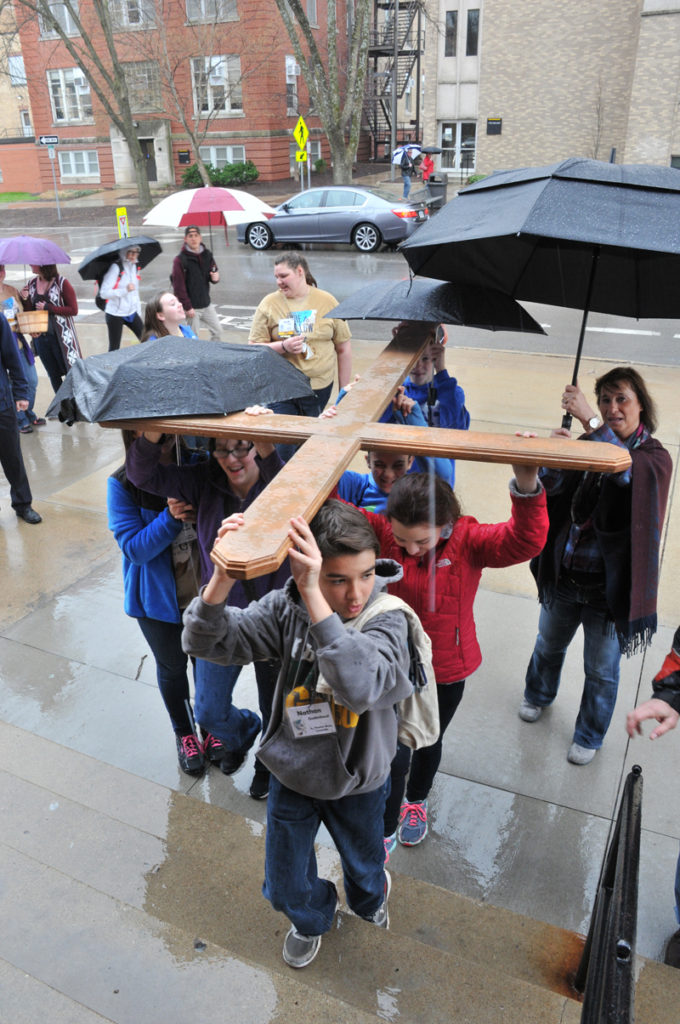 Lindsay Steele Rain-soaked youths from St. Thomas More Parish-Coralville and St. Mary Parish-Oskaloosa carry a cross up the stairs of St. Mary Church in Iowa City during the Junior High Youth Rally April 10. 
