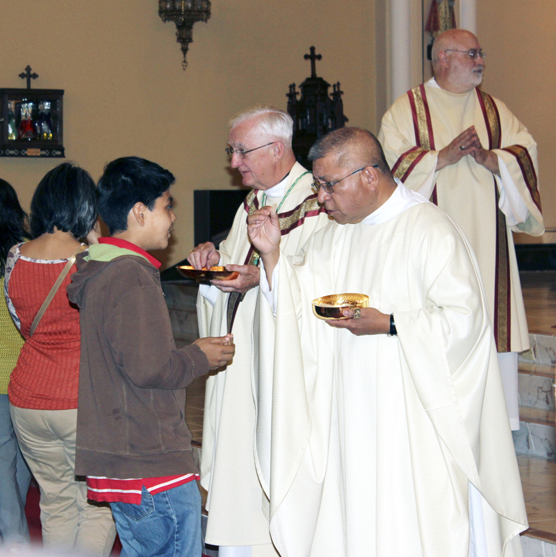 Barb Arland-Fye Father Rudolph Juarez, right, and Bishop Martin Amos distribute Communion during Mass on May 7 at Sacred Heart Cathedral in Davenport where Spanish-speaking Catholics were gathered to celebrate the Year of Mercy. 