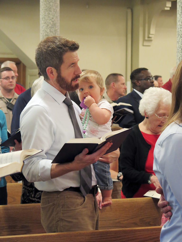 Anne Marie Amacher Al Budelier holds his youngest daughter Sarah during Mass at St. Paul the Apostle Church in Davenport.