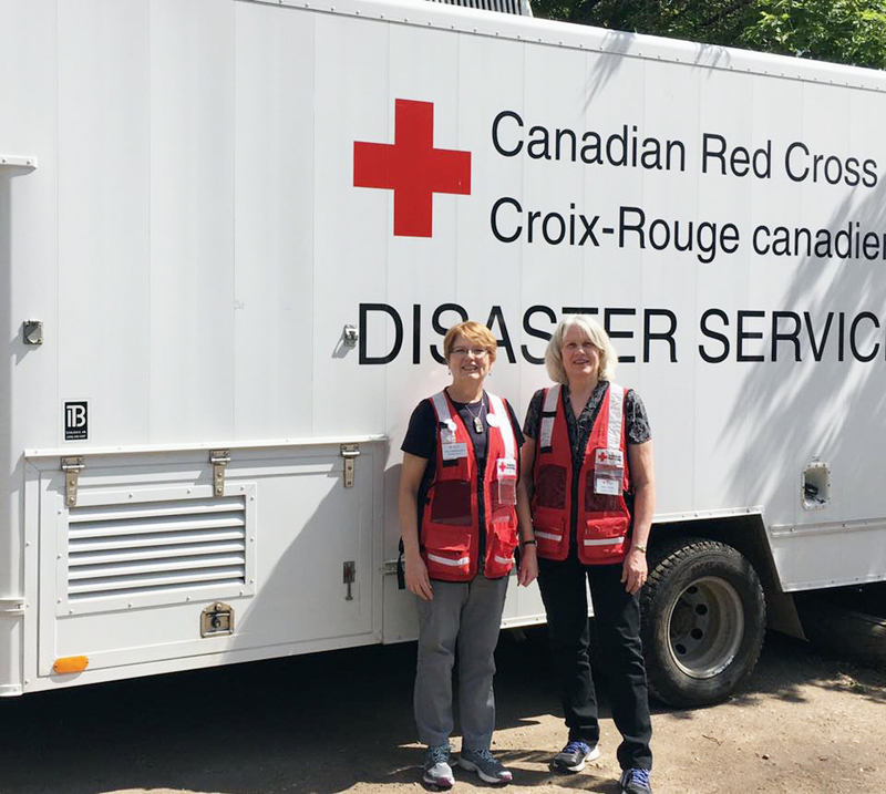 Contributed Jean Jacobs and Pat D’Alessandro pose in front of a Canadian Red Cross disaster vehicle. The two Diocese of Davenport parishioners are volunteers with the American Red Cross out of Moline, Ill. They are in Canada helping with disaster relief from the wildfires ravaging the country.