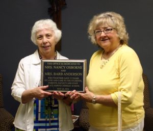 Kat Gay Nancy Osborne, left, and Barb Anderson hold a dedication plaque during a celebration of their retirement from All Saints Catholic School in Davenport.  