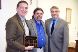Jean Bormann L’Arche Clinton Community Leader Devin Land, left, accepts the Clinton Human Rights Commission Award from Clinton Mayor Mark Vulich, right, on behalf of the L’Arche Clinton community May 16. Ed Gall, center, nominated L’Arche for the award. 