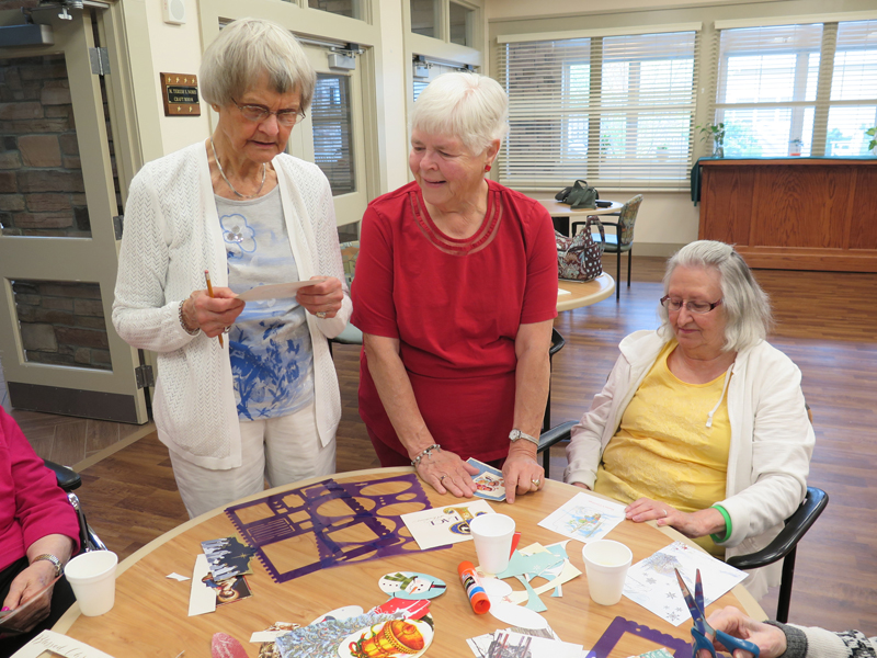 Anne Marie Amacher Catholic Service Board members Kay Perry, left, and Mary Ellen Olson decide on a pattern for Kahl Home resident Sylvia Heaton to cut for a project for the bazaar in October. 