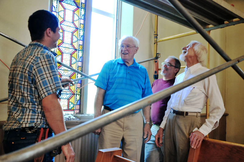 Lindsay Steele Dexter Christy, co-owner of Hershey Stained Glass Studios, speaks to St. Peter Parish historian Jack Ruth, accountant Curt Barkalow and pastor Father Ed Dunn underneath scaffolding Aug. 19 at St. Peter Church in Cosgrove. The parish has implemented an adopt-a-window program to pay for repairs to the 100-plus- year-old stained glass windows in the church.
