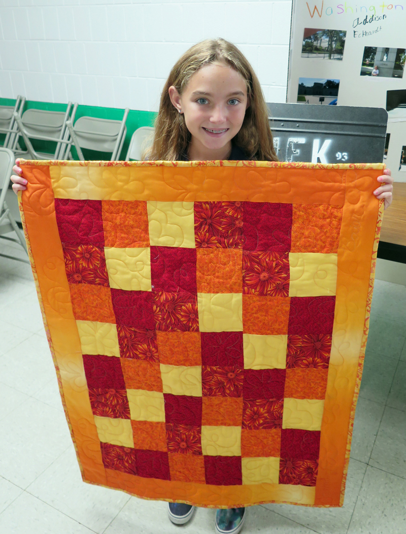 Anne Marie Amacher Camdyn Baier holds a quilt that she and her grandma made over the summer. The quilt was for a summer fun fair project at John F. Kennedy Catholic School in Davenport. 