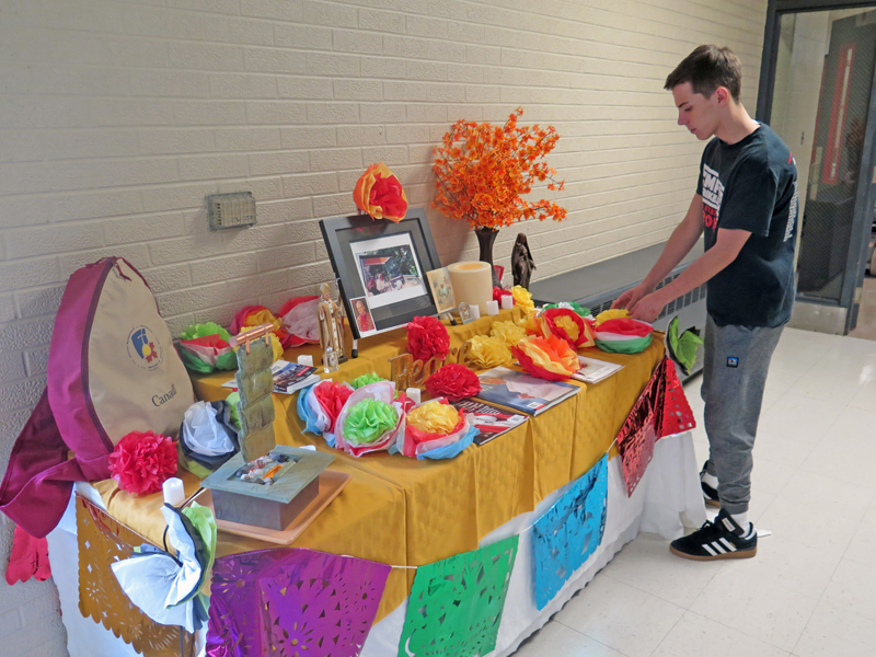 Anne Marie Amacher Senior Joe Field touches up one of two Day of the Dead displays at Assumption High School in Davenport. One altar is dedicated to St. Teresa of Kolkata and the other to St. John Paul II. 